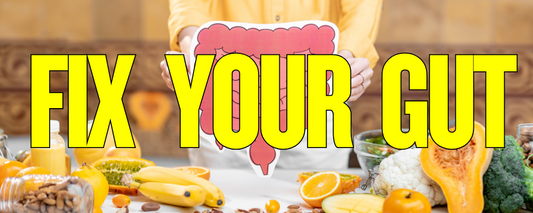 Person holding a cartoon image of a large intestine behind a table full of fresh fruits, vegetables, and healthy foods with bold yellow text that says "Fix Your Gut"